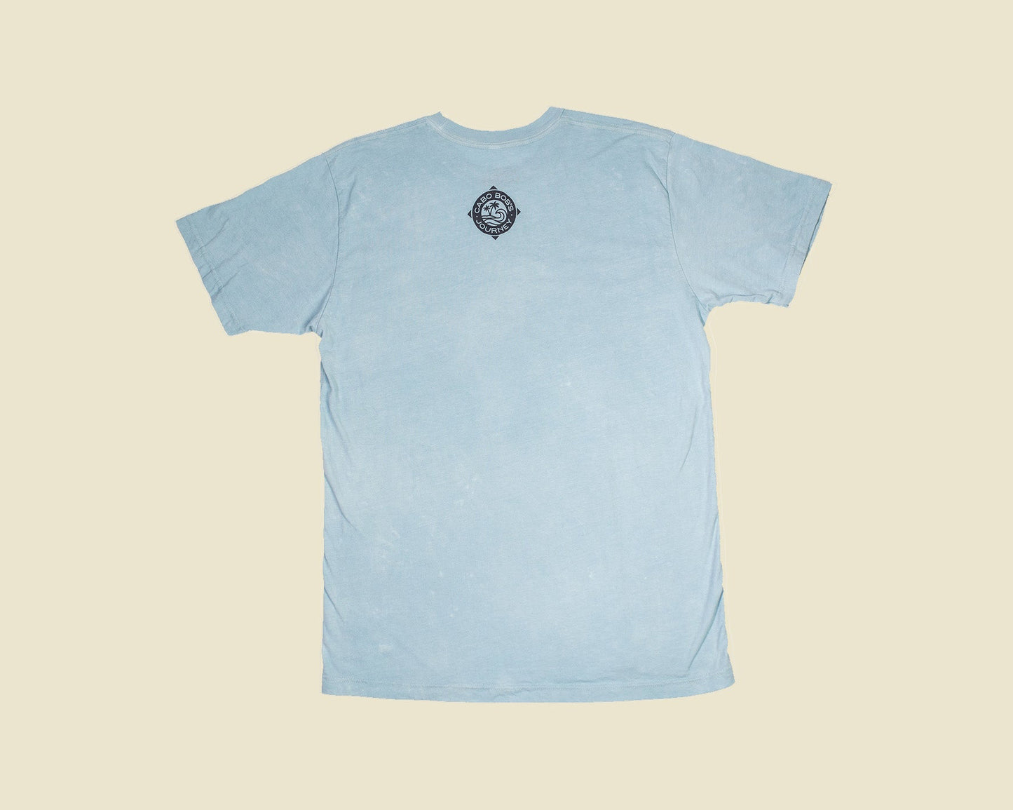 Light blue t-shirt with a small logo on the neck against a beige background