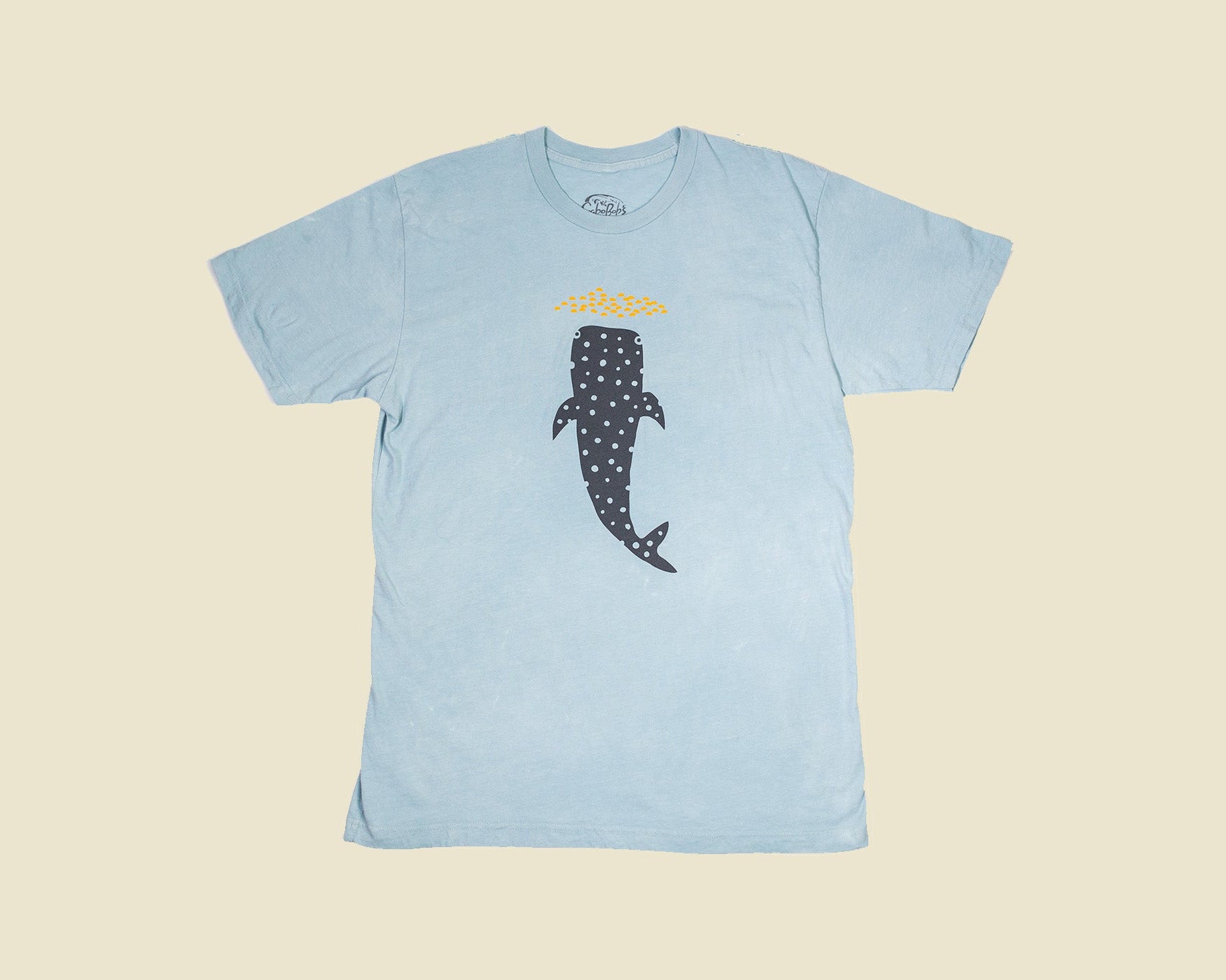 Light blue t-shirt with a whale design on a beige background