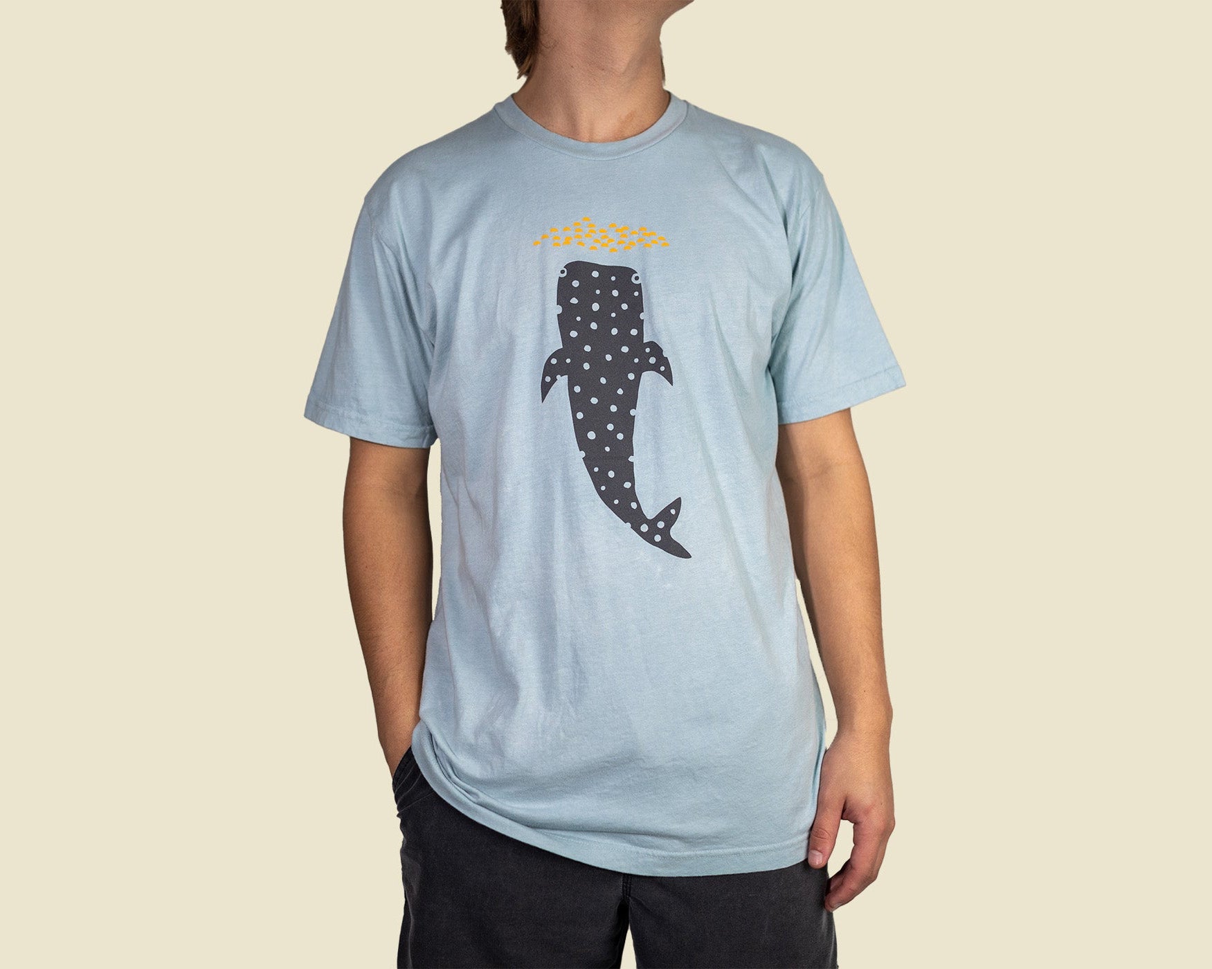Light blue t-shirt with a whale shark design on a beige background